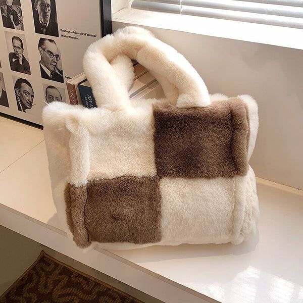 Pluche handtas met blokpatroon in wit en bruin, gelegen op een vensterbank. Modieuze damesaccessoire, perfect voor winterse outfits.
