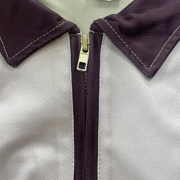 Paarse en witte poloshirt met halve rits, close-up van kraag en rits. Modieuze herenkleding, sportieve stijl, hoogwaardige stof.