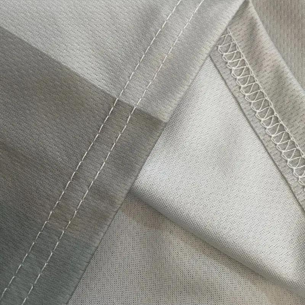Grijze poloshirtstof met halve rits, close-up van stiksel en textuur, ademend en duurzaam materiaal, geschikt voor sportkleding.