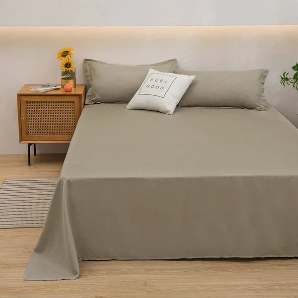 Beige beddengoed set met kussens en "Feel Good" kussen, naast houten nachtkastje met zonnebloemen, in moderne slaapkamer.