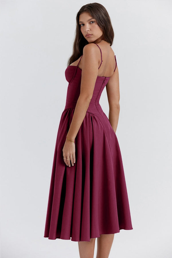 Jurk in bordeauxrood, mouwloos met een geplooide rok, gedragen door een vrouw. Perfect voor avondkleding of formele evenementen.