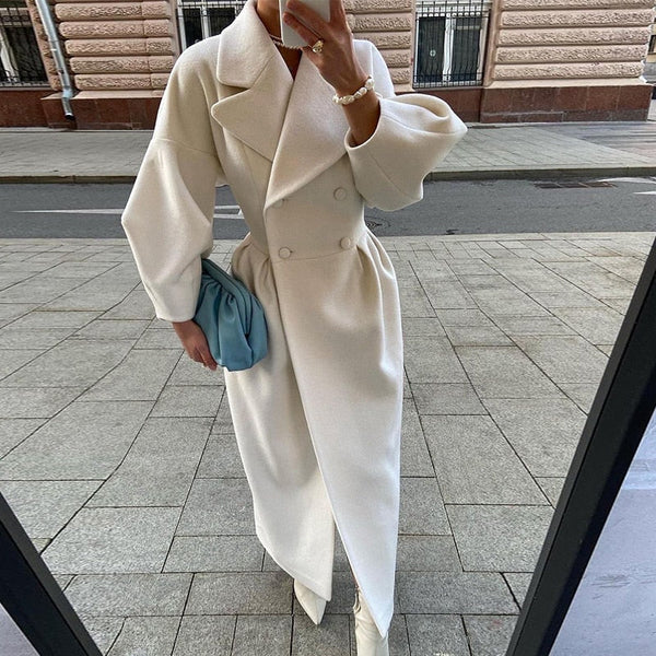 Elegante witte damesmantel met dubbele rij knopen, lange mouwen en een blauwe clutch. Perfect voor herfstmode en stijlvolle straatkleding.