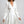 Vrouw in elegante witte satijnen jurk met lange mouwen en knoopsluiting, modieuze kleding, stijlvolle damesmode, chique avondjurk.