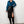 Vrouw in blauwe blouse en zwarte leren rok met hoge split, gecombineerd met hoge laarzen. Modieuze dameskleding, elegante outfit.