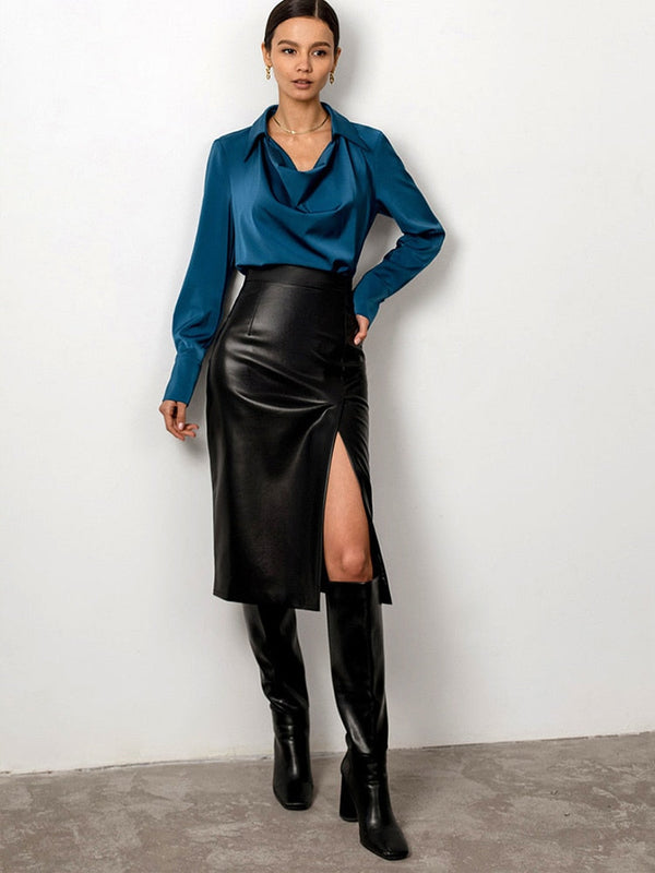 Vrouw in blauwe blouse en zwarte leren rok met hoge split, gecombineerd met hoge laarzen. Modieuze dameskleding, elegante outfit.
