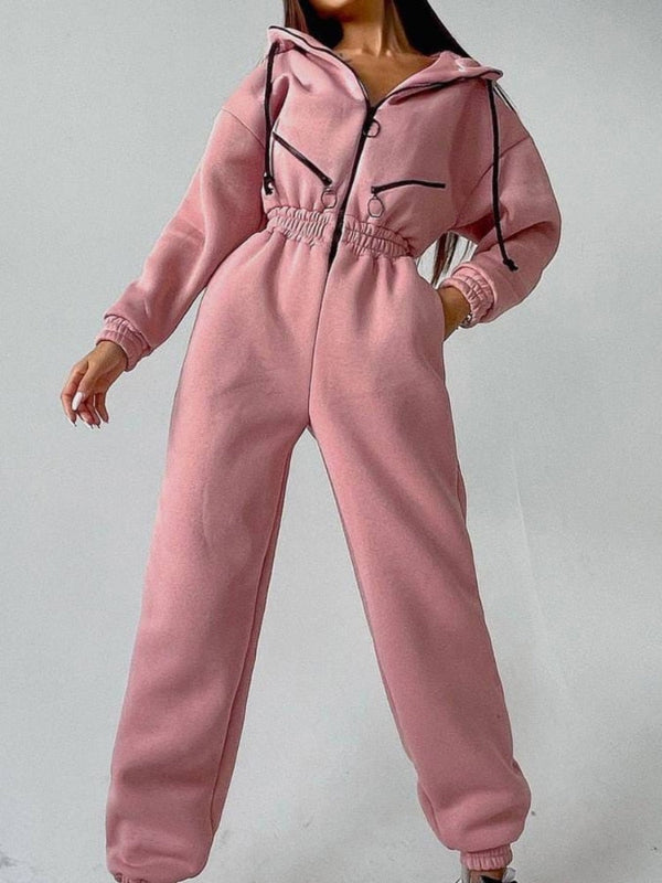 Roze damesjumpsuit met capuchon, elastische taille en zwarte accenten. Modieuze loungewear, comfortabele pasvorm, trendy streetwear outfit.