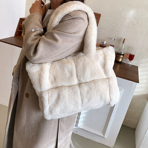 Vrouw met stijlvolle, witte pluchen schoudertas, draagt beige jas. Luxe modeaccessoire, perfect voor winterse outfits. Trendy en elegant design.
