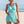 Vrouw in turquoise strandjurk met gehaakt patroon op zonnig strand. Zomermode, strandkleding, damesjurk, strandvakantie.
