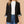 Vrouw in zwarte blazer met opgerolde mouwen, witte trui en blauwe jeans. Modieuze dameskleding, casual chic outfit voor dagelijks gebruik.
