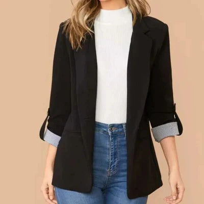 Vrouw in zwarte blazer met opgerolde mouwen, witte trui en blauwe jeans. Modieuze dameskleding, casual chic outfit voor dagelijks gebruik.