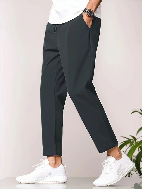 Man draagt zwarte chino broek en witte sneakers, casual mode, zijaanzicht. Comfortabele herenkleding, moderne stijl, dagelijkse outfit.