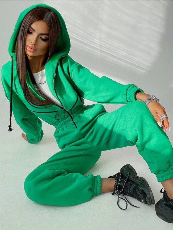 Groene damesjumpsuit met capuchon, gedragen door model. Trendy streetwear, comfortabele pasvorm, ideaal voor casual en sportieve looks.