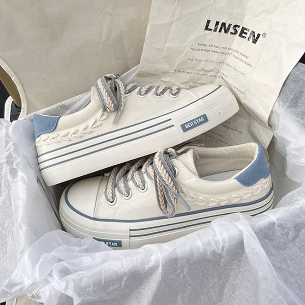 Witte canvas sneakers met blauwe accenten en gevlochten veters in een doos. Trendy casual schoenen, perfect voor dagelijks gebruik.