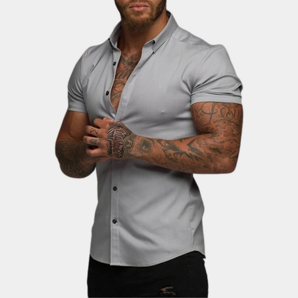 Grijs herenoverhemd met korte mouwen, getailleerd design, gedragen door getatoeëerde man. Stijlvol en modern, ideaal voor casual en zakelijke looks.