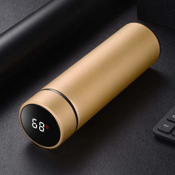 Gouden slimme thermosfles met temperatuurweergave op LED-display, liggend op zwart oppervlak. Ideaal voor warme en koude dranken.