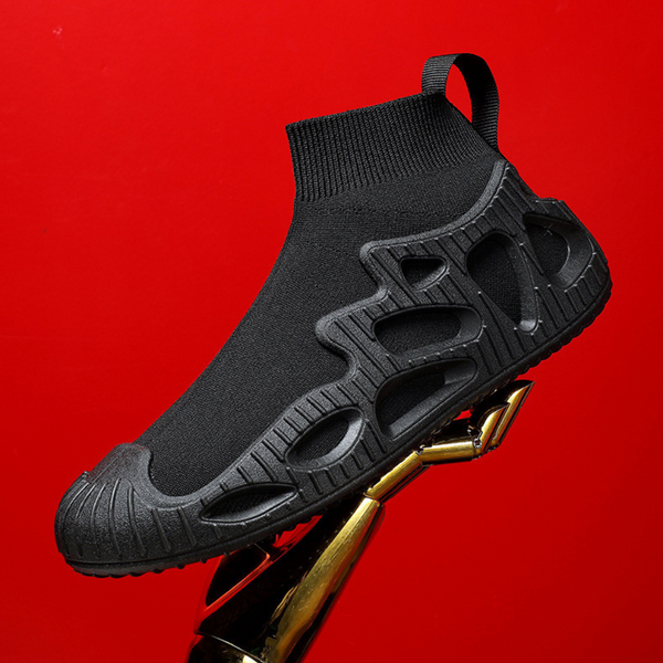 Zwarte sok sneaker met futuristisch ontwerp en rubberen zool, zwevend op rode achtergrond. Moderne unisex schoenen, trendy en comfortabel.