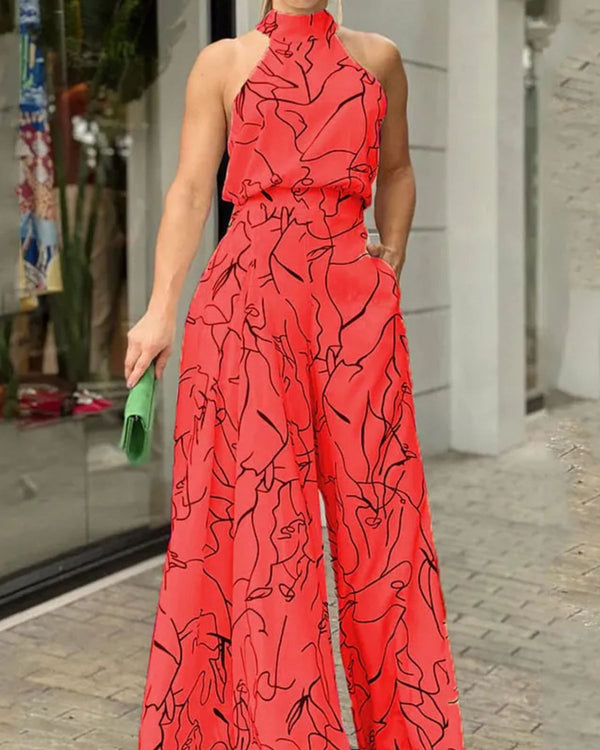 Rode jumpsuit met abstracte zwarte lijnen, mouwloos en halternek, gedragen door vrouw met groene clutch. Modieuze dameskleding voor zomer.