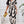 Vrouw in elegante zwart-witte maxi-jurk met abstract patroon, gouden clutch in hand. Perfecte outfit voor chique evenementen en modieuze gelegenheden.