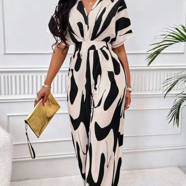 Vrouw in elegante zwart-witte maxi-jurk met abstract patroon, gouden clutch in hand. Perfecte outfit voor chique evenementen en modieuze gelegenheden.