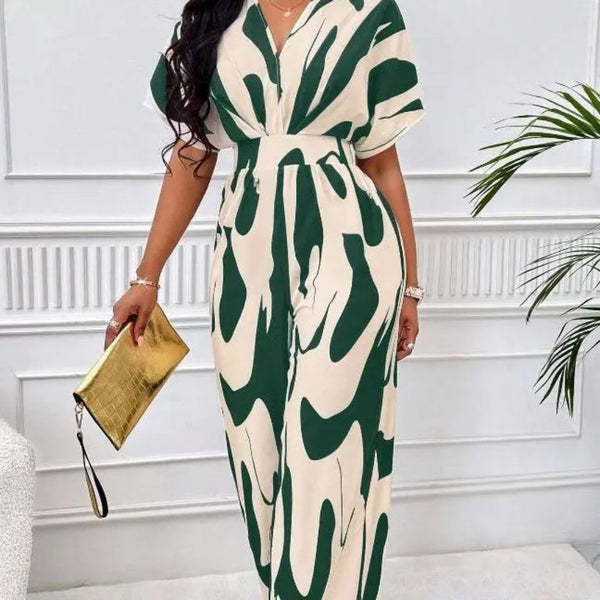 Vrouw in stijlvolle groene en witte jumpsuit met abstract patroon, gouden clutch in hand, moderne mode, elegante outfit, trendy kledingstijl.