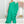 Vrouw in elegante, asymmetrische groene jurk met wijde pijpen, perfecte outfit voor avondfeesten. Trendy mode, stijlvolle dameskleding.