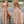 Beige maxi-jurk met halternek en open rug, gedragen door model. Elegante avondjurk, perfect voor zomerse evenementen en bruiloften.