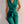 Vrouw in elegante groene jumpsuit met gouden knopen en strikceintuur, modieuze outfit, stijlvolle dameskleding, trendy modeaccessoires.