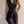 Elegante zwarte jumpsuit met mouwloos ontwerp, gouden knopen en strikceintuur, ideaal voor chique avondkleding en modieuze gelegenheden.