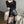 Vrouw in zwarte leren shorts en top met lange mouwen, poseert in moderne woonkamer. Modieuze dameskleding, trendy outfit, stijlvolle look.