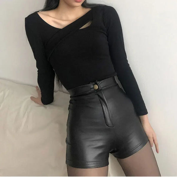 Vrouw in zwarte top met asymmetrische halslijn en hoge taille leren shorts, modieuze outfit, trendy dameskleding, minimalistisch design.