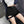 Vrouw draagt zwarte cargoshorts met zakken en riem, gecombineerd met een witte crop top en blauwe mouwen, trendy streetwear mode.