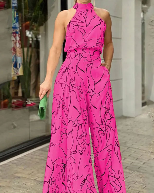 Vrouw in felroze jumpsuit met abstracte zwarte lijnen, halternek en wijde pijpen, houdt groene clutch vast. Modieuze dameskleding, straatstijl.