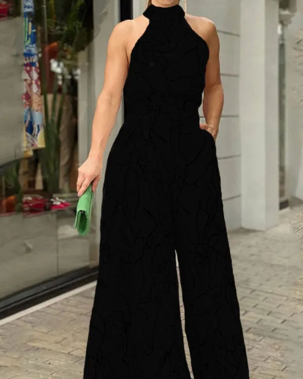 Vrouw in elegante zwarte jumpsuit met halternek, groene clutch in hand, staand op stoep voor winkel. Mode, avondkleding, stijlvolle outfit.