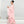 Vrouw in elegante roze avondjurk met lange mouwen en golvende lagen, staand tegen een grijze achtergrond. Perfect voor mode en avondkleding.