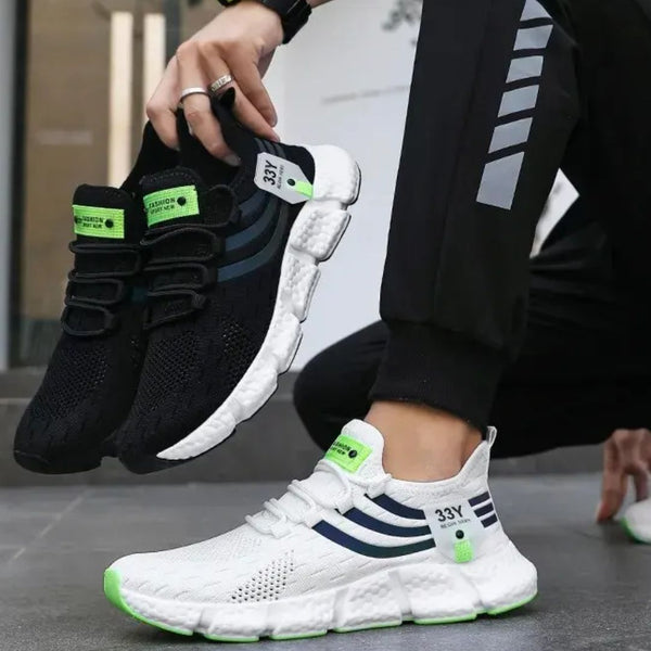 Twee paar sportieve sneakers, zwart en wit, met groene accenten en 33Y-logo, gedragen door een persoon in sportkleding. Moderne hardloopschoenen.