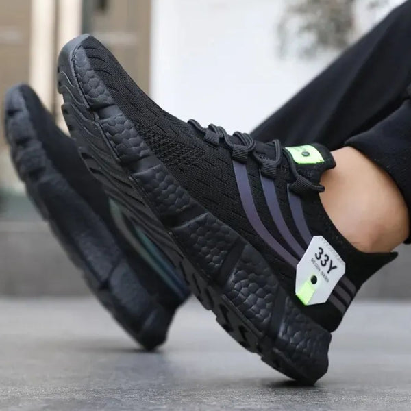 Zwarte sportschoenen met dikke zool en paarse strepen, gedragen door persoon. Comfortabele hardloopschoenen, ideaal voor sport en dagelijks gebruik.