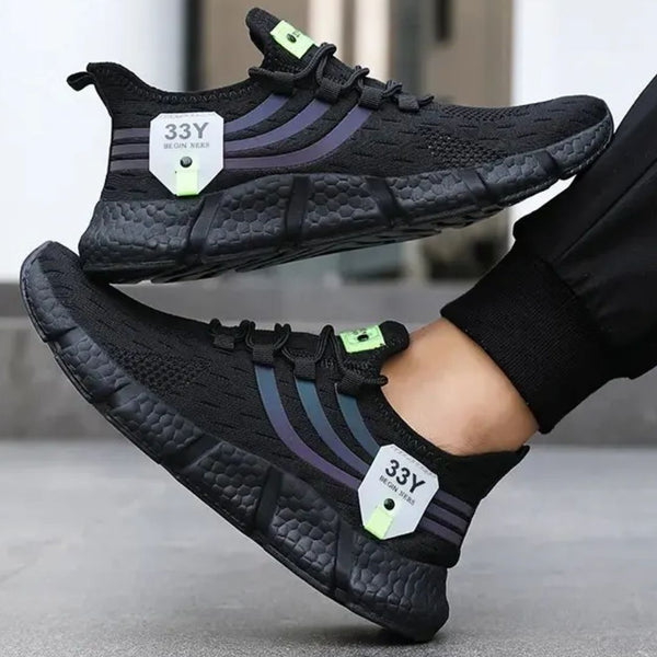 Zwarte sportschoenen met paarse strepen en groene accenten, ademend mesh bovenwerk, comfortabele zool, ideaal voor hardlopen en fitness.