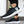 Zwarte sportschoenen met witte zool, groene accenten en label 