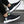 Zwarte sportschoenen met witte zool en groene accenten, gedragen door een persoon. Comfortabele hardloopschoenen voor heren, modern design.