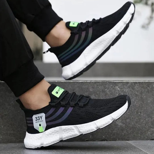 Zwarte sportschoenen met witte zool en groene accenten, gedragen door een persoon. Comfortabele hardloopschoenen voor heren, modern design.