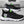 Zwarte sportschoenen met witte zool, groene accenten en reflecterende strepen, ideaal voor hardlopen en casual gebruik. Comfortabel en stijlvol ontwerp.