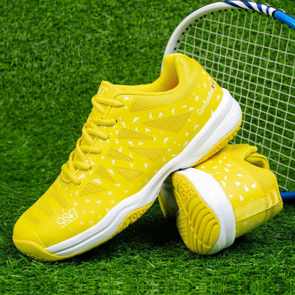 Gele tennisschoenen met witte accenten op gras, naast een tennisracket. Sportieve sneakers voor tennis, comfortabele grip, stijlvol ontwerp.