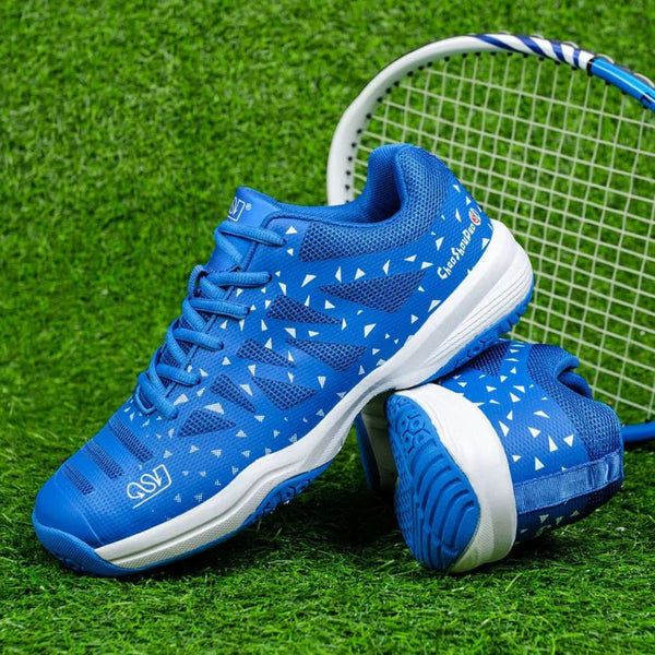Blauwe tennisschoenen met witte driehoekpatronen op kunstgras, naast een tennisracket. Ideaal voor sport en outdoor activiteiten.