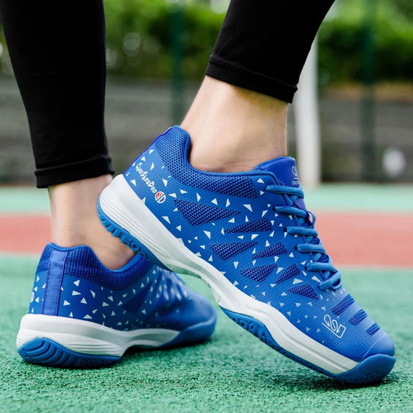 Blauwe tennisschoenen met witte driehoekige patronen, gedragen op een tennisbaan. Comfortabele sportschoenen voor optimale prestaties.