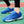 Blauwe sportschoenen met witte driehoekige patronen, gedragen op een groen sportveld. Ideaal voor hardlopen en fitness. Comfortabele en stijlvolle sneakers.