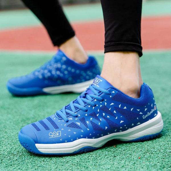 Blauwe sportschoenen met witte driehoekige patronen, gedragen op een groen sportveld. Ideaal voor hardlopen en fitness. Comfortabele en stijlvolle sneakers.