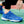 Blauwe sportschoen met witte driehoekige patronen, gedragen op een groen sportveld. Ideaal voor tennis, hardlopen en fitness. Comfortabel en stijlvol ontwerp.