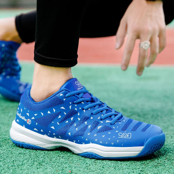 Blauwe sportschoen met witte driehoekige patronen, gedragen op een groen sportveld. Ideaal voor tennis, hardlopen en fitness. Comfortabel en stijlvol ontwerp.