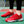 Rode tennisschoenen met witte patronen op een groene tennisbaan, naast een tennisracket. Ideaal voor sport en outdoor activiteiten.