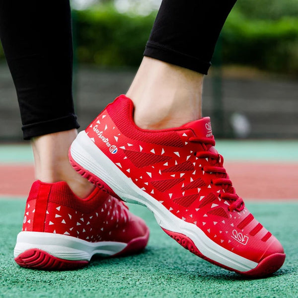 Rode sportieve tennisschoenen met witte driehoekige patronen, gedragen op een tennisbaan. Ideaal voor tennis, comfortabele grip en stijlvol ontwerp.